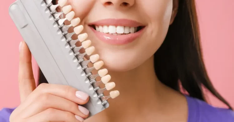 Patient holding dental veneers colour chart sample to her teeth.
