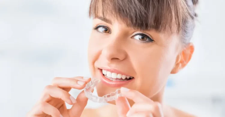 Invisalign patient holding her retainers with two hands and smiling.