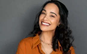 Woman with dark hair smiling showing off her bright, white teeth.