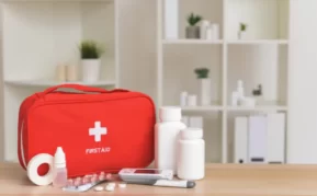 A red dental first aid kit on a table with the contents in front.